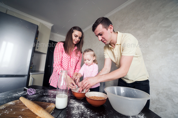 Dad, mom and daughter together in the kitchen Stock Photo by simbiothy