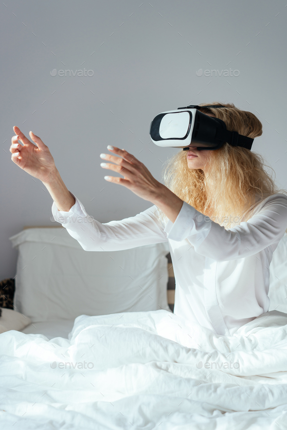 Girl sitting on a bed with VR headset Stock Photo by simbiothy | PhotoDune