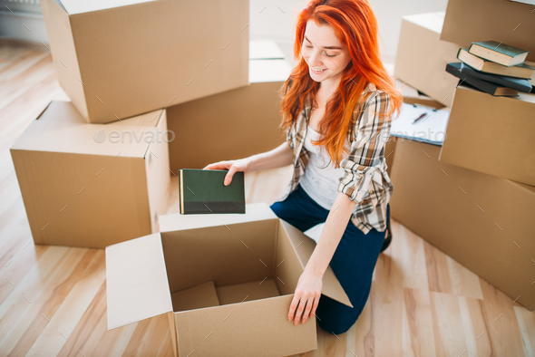 Woman unpacking cardboard boxes in new home Stock Photo by NomadSoul1