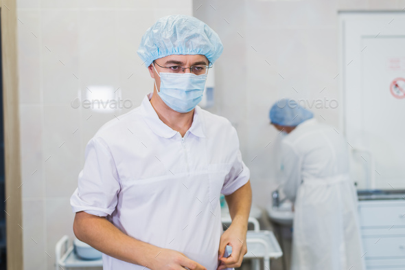 Thoughtful male surgeon wearing surgical mask in hospital Stock Photo by romankosolapov