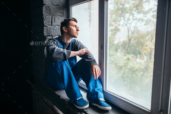 Depressed man sitting on the window sill, psycho Stock Photo by NomadSoul1