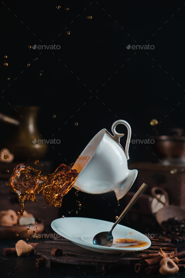 Falling coffee cup with a dynamic splash in a dark scene with cezve, saucer and teaspoon Stock Photo by dinabelenko