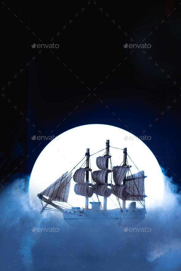 Sail ship in light of full moon. Wooden model on dark background. Conceptual marine still life. Stock Photo by dinabelenko