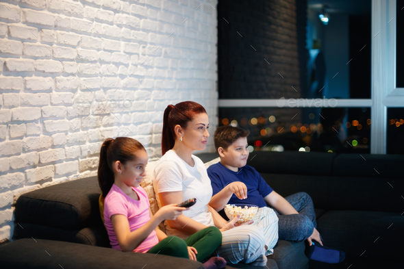Single Mother And Children Watching TV At Night Stock Photo by diego_cervo