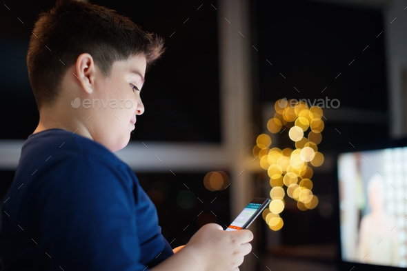 Unattended Boy Chatting And Typing On Mobile Phone At Night Stock Photo by diego_cervo