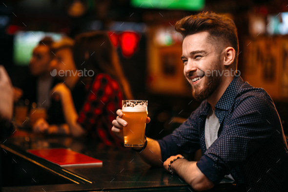 Man drinks beer at the bar counter in a sport pub Stock Photo by NomadSoul1