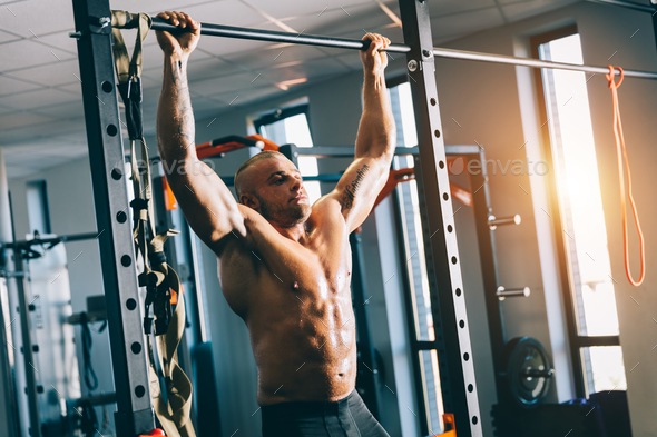 Muscular man doing pull-ups in a gym. Stock Photo by photocreo | PhotoDune
