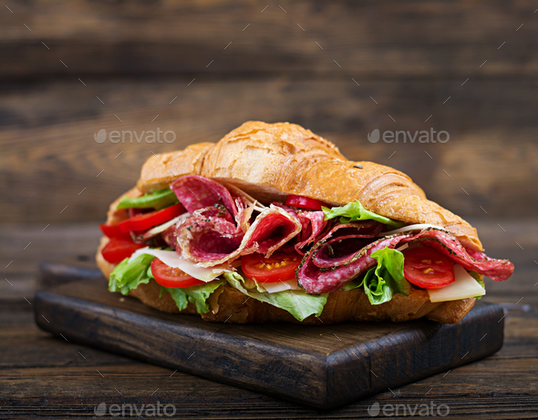 Tasty breakfast. Appetizing croissant with salami and, cheese and tomatoes Stock Photo by Timolina