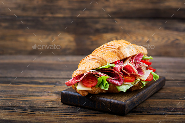 Tasty breakfast. Appetizing croissant with salami and, cheese and tomatoes Stock Photo by Timolina