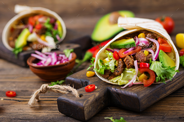 Mexican tacos with beef in tomato sauce and avocado salsa Stock Photo by Timolina
