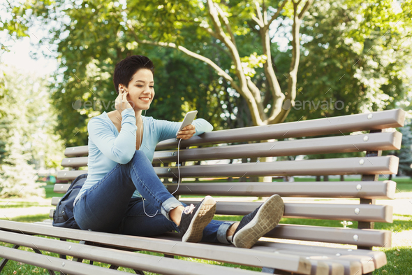 Attractive woman listening to music outdoors Stock Photo by Milkosx