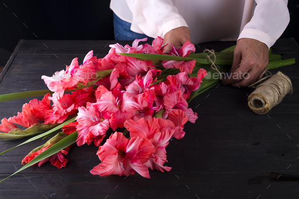 women\'s hands create a bouquet of flowers of gladiolus Stock Photo by lyulkamazur
