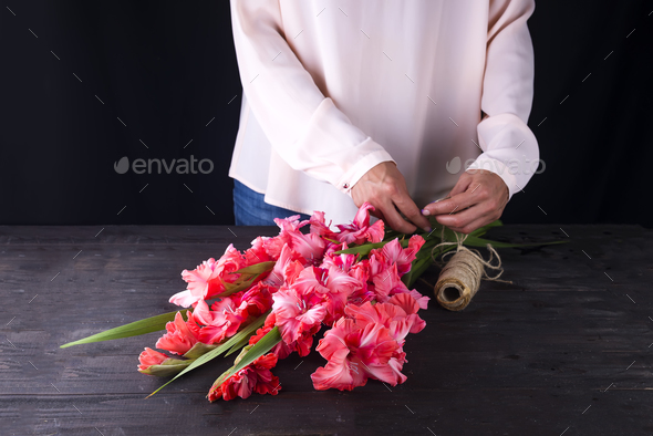 women\'s hands create a bouquet of flowers of gladiolus Stock Photo by lyulkamazur