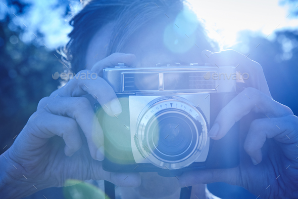 Woman taking pictures with vintage camera. Backlight. Travel background Stock Photo by ABBPhoto