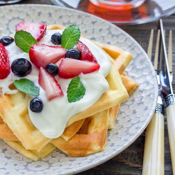 Homemade belgian waffles with yogurt, strawberry and blueberry, breakfast time, square Stock Photo by iuliia_n