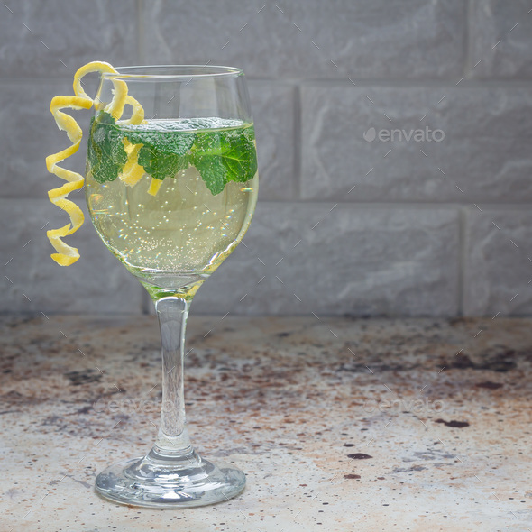 Spritzer cocktail with white wine, mint and ice, decorated with spiral lemon zest, square format Stock Photo by iuliia_n