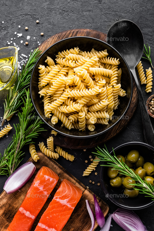 Pasta, salmon fish and ingredients for cooking on black background, top view. Italian food Stock Photo by sea_wave