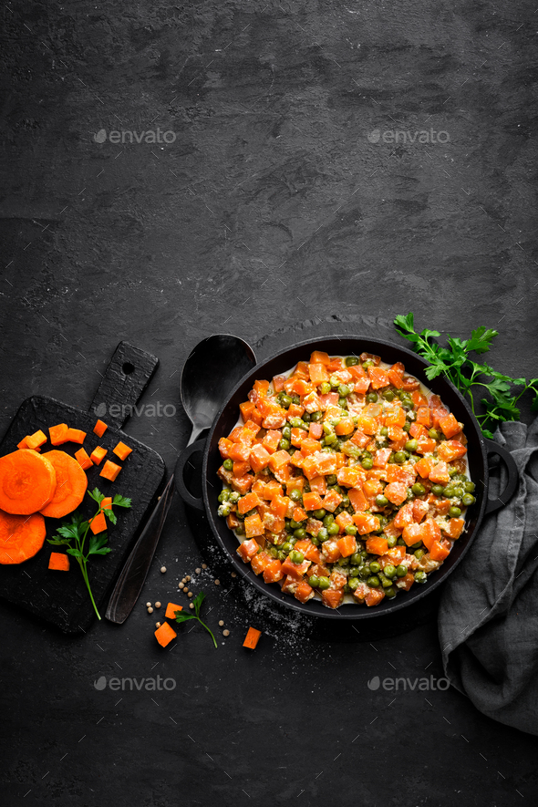 Carrot braised with fresh green peas in creamy milk sauce in stewpan, vegetable saute Stock Photo by sea_wave