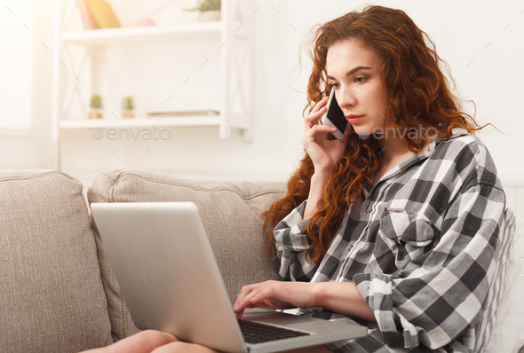 Girl with laptop and mobile sitting on beige couch. Stock Photo by Milkosx