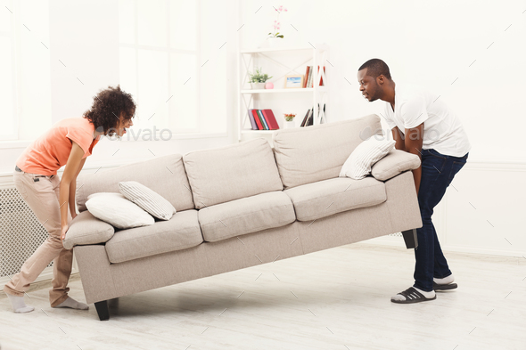 African-american couple placing sofa at new home Stock Photo by Milkosx