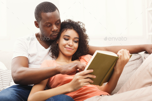 HAppy black couple reading together at home Stock Photo by Milkosx