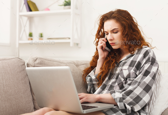Girl with laptop and mobile sitting on beige couch. Stock Photo by Milkosx