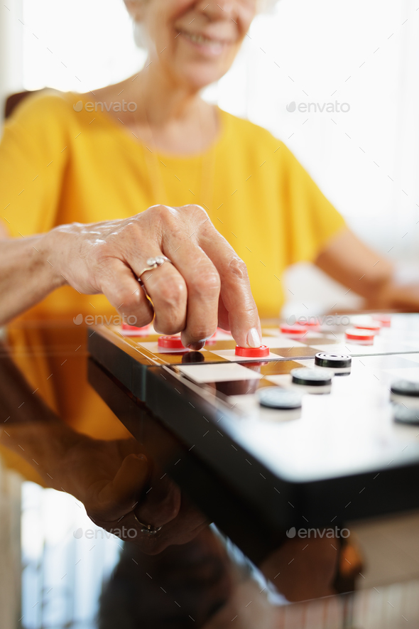 Grandma Playing Checkers Board Game In Hospice Stock Photo by diego_cervo