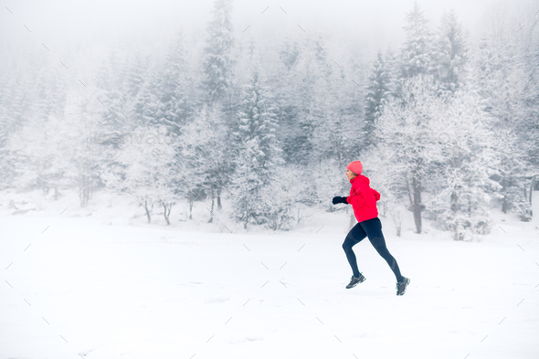 Girl trail running on snow in winter mountains Stock Photo by blas