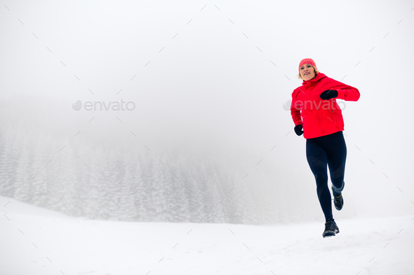 Trail running woman on snow in winter mountains Stock Photo by blas