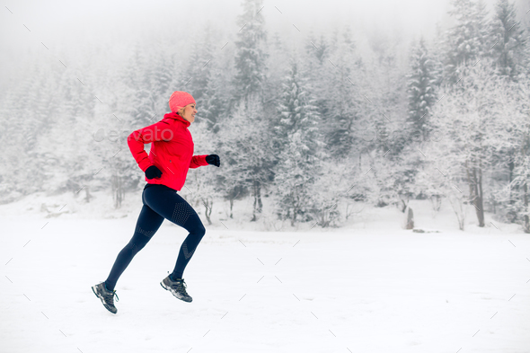 Woman trail running on snow in winter mountains Stock Photo by blas
