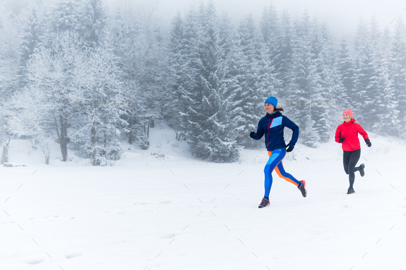 Two women trail running on snow in winter mountains Stock Photo by blas