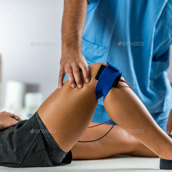 Electrical stimulation in physical therapy. Therapist positionin Stock Photo by microgen