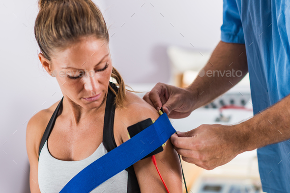 Electrical stimulation in physical therapy. Therapist positionin Stock Photo by microgen