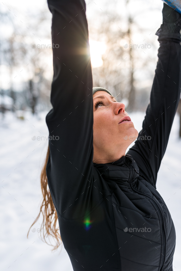 Female athlete exercising in park in winter Stock Photo by microgen