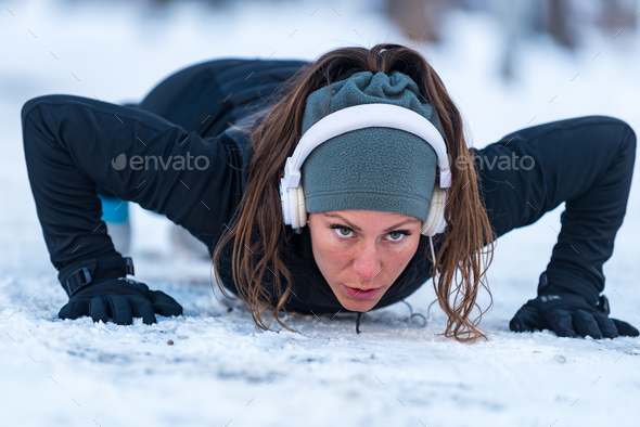 Female athlete exercising in park in winter Stock Photo by microgen