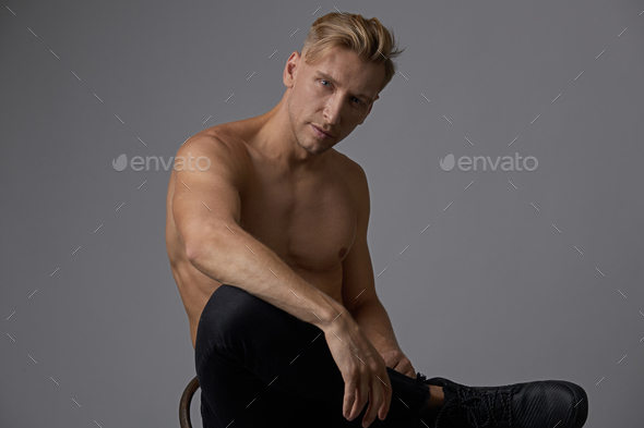 Attractive young man posing with naked torso sitting on a chair Stock Photo by arthurhidden