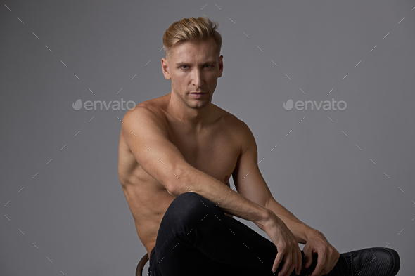 Attractive young man posing with naked torso sitting on a chair Stock Photo by arthurhidden