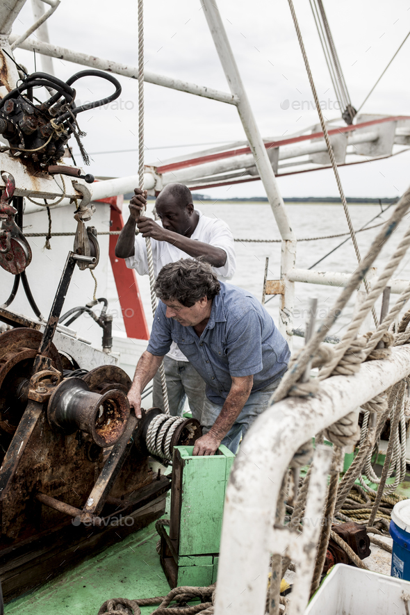 Commercial fishermen working on the deck of a shrimp boat Stock Photo by wollwerth