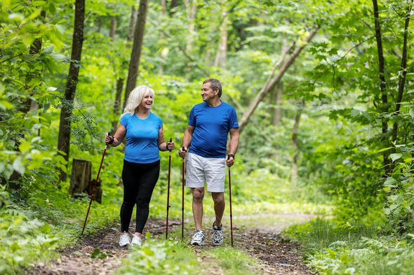 Elderly couple enjoying summer walk in the forest. Stock Photo by photocreo