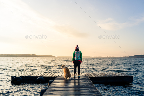 Woman with dog enjoy sunrise at lake, backpacker Stock Photo by blas