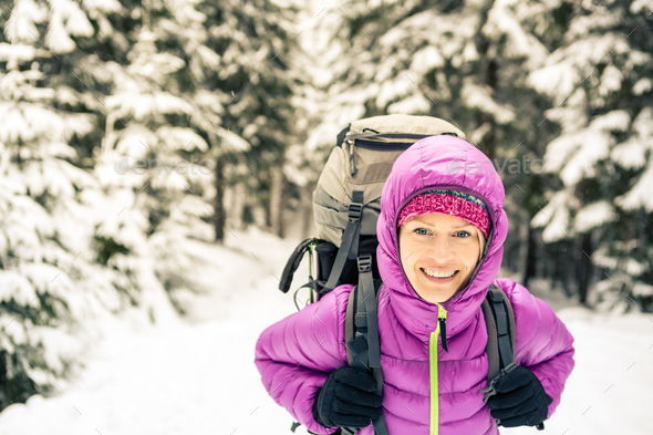 Happy woman walking in winter forest with backpack Stock Photo by blas