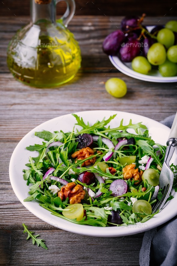 green salad bowl with arugula, walnuts, goat cheese, red onion and grapes Stock Photo by nblxer