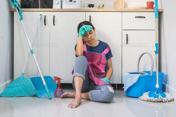 Tired young woman sitting on kitchen floor Stock Photo by kitzstocker