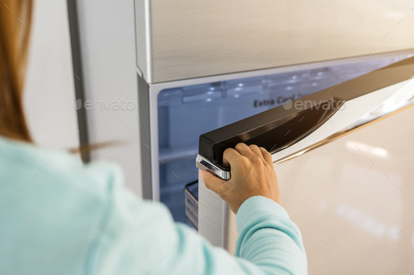 young woman hand opening refrigerator door Stock Photo by kitzstocker