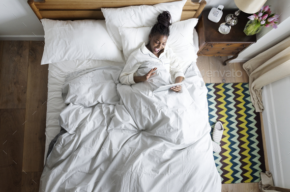 Smiling African American woman on bed video chatting Stock Photo by Rawpixel
