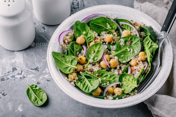 Healthy green salad bowl with spinach, quinoa, chickpeas and red onions Stock Photo by nblxer