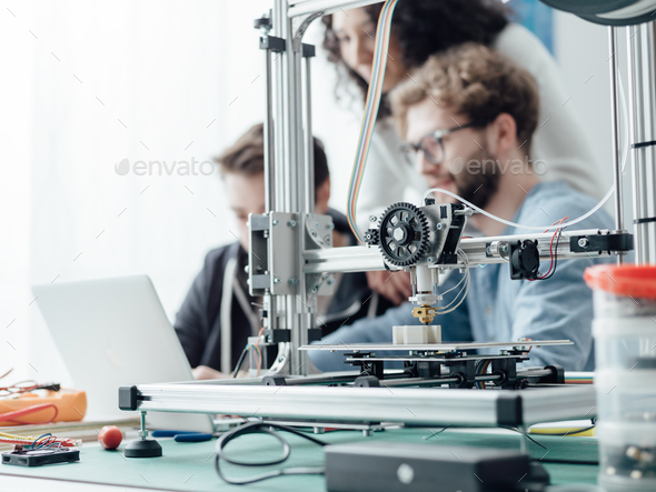 Group of students using a 3D printer and a laptop Stock Photo by stokkete