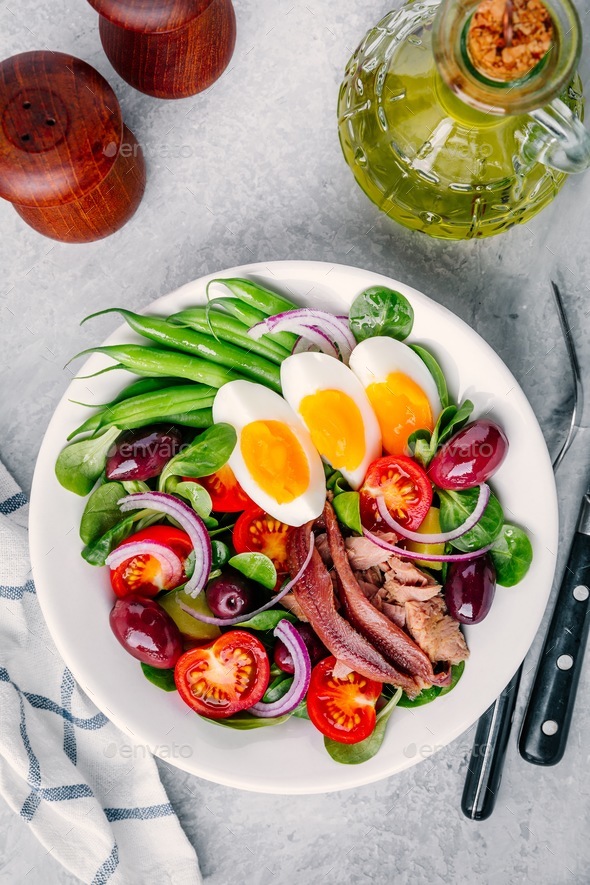 nicoise salad with tuna, anchovies, eggs, green beans, olives, tomatoes, red onions and salad leaves Stock Photo by nblxer