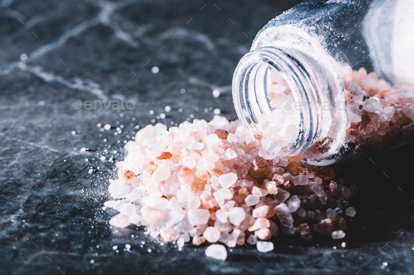 Himalayan pink salt spilled from a glass jar Stock Photo by photocreo