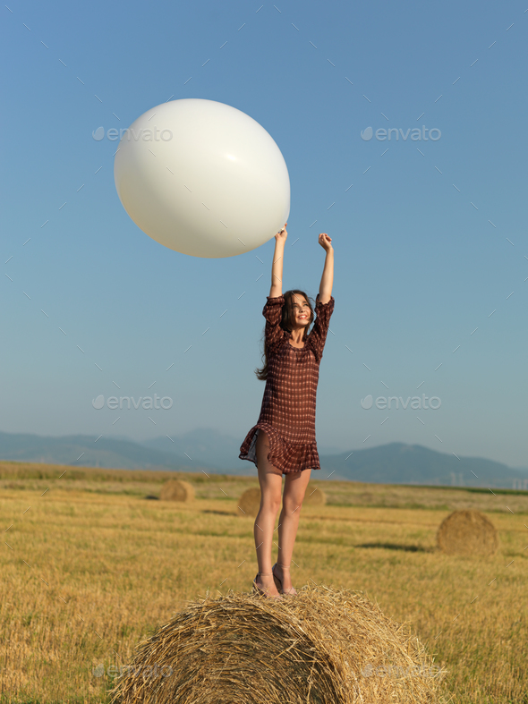 happy woman jumping white balloon hay stack Stock Photo by shotsstudio